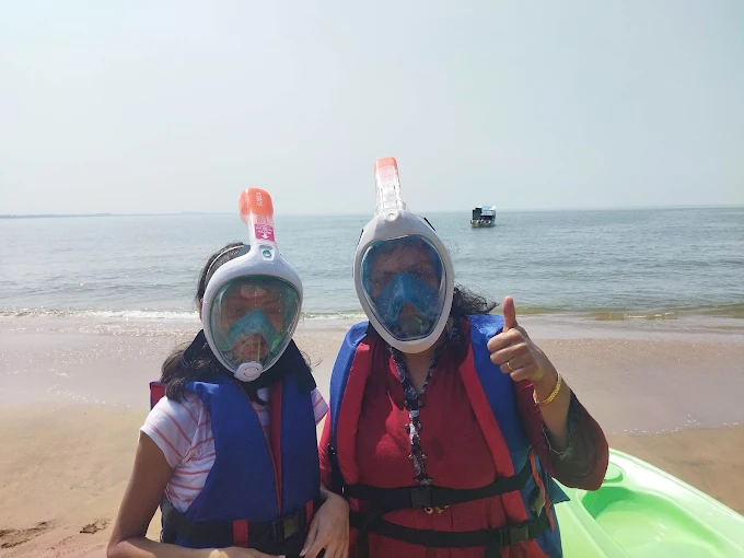 Two guests wearing full-face snorkel masks and life jackets on the beach
